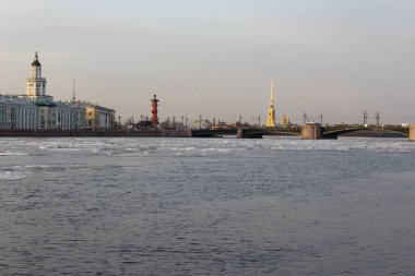 St. Petersburg, Rusya - 23 Mart 2016. Kunstkammer, Rostral Sütunu, Peropavlovskaya Kalesi ve Neva nehir yatağındaki Saray Köprüsü 'nün baharın ilk günbatımında buz akıntısıyla manzarası