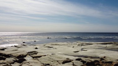 Güneşli bir günde kıyıya yakın yüzen buzlarla dolu ilkbahar körfezi