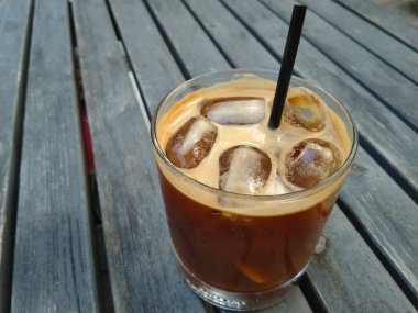 Bir bardak kahve, tonik ve ahşap masada buz. 