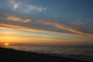 Doymuş gökyüzü ve bulutlarla denizdeki güzel altın gün batımı