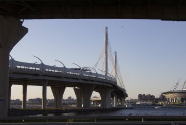 Otoban virajının ve kırmızı refleks günbatımında kablo destekli köprünün direklerinin görüntüsü