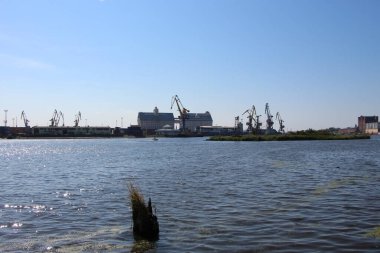 Kalininingrad, Rusya - 8 Eylül 2021. Su manzarası, iskele vinçlerinin siluetleri, konteynır alanları ve Kaliningrad limanının binaları