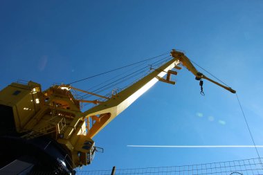 Kabinin alt görüntüsü ve sarı liman vincinin patlaması beyaz bir uçağın ayak iziyle gökyüzüne karşı.