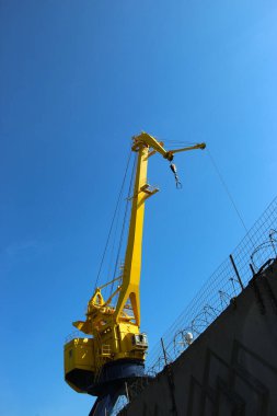 Kabinin alt görüntüsü ve gökyüzüne karşı sarı liman vincinin patlaması.