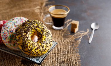 Masanın üstünde renkli, lezzetli kahvaltı çörekleri ve yanında kahve var..