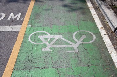 Yeşil bisiklet yolundaki beyaz bisiklet boyası. Bisikletçiler tarafından kullanılmak üzere boyalı çizgilerle işaretlenmiş bir yolun bir bölümü..