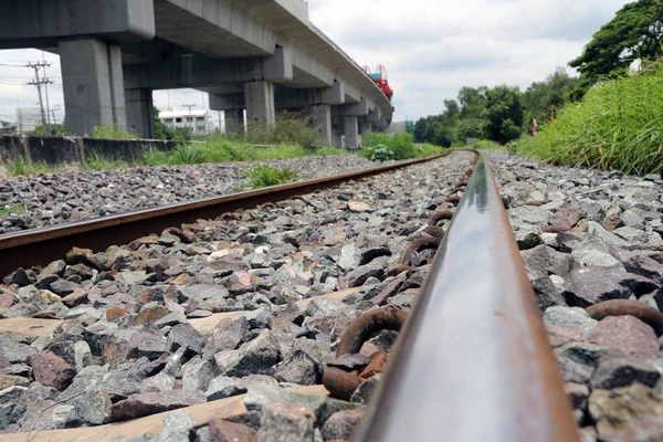 Railroad tracks and rocks in Thailand, metal railway of train and background green tree.