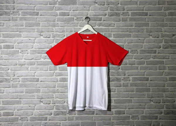 シャツにインドネシアのフラグとレンガのパターンの壁紙と壁にかかって 赤と白の水平方向の色 — ストック写真