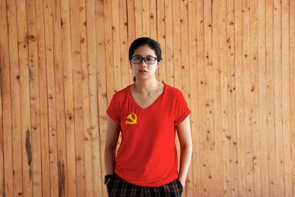 身穿中国共产党旗彩衣 双手插在裤子口袋里 头戴木制墙 头戴金锤 头戴红色镰刀的女性 — 图库照片