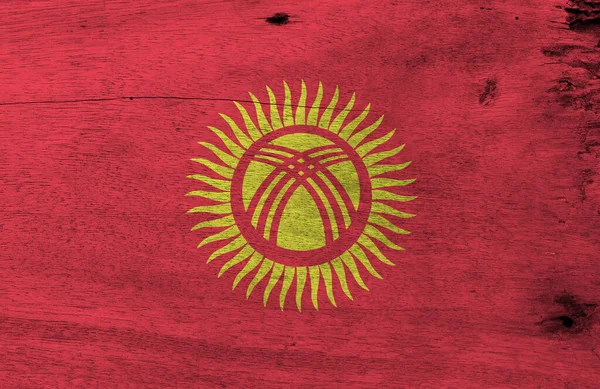 木製のプレートの背景にキルギスの旗 キルギスの旗のテクスチャを粉砕し 40枚の均一な間隔の光線で黄色の太陽と赤のフィールド — ストック写真