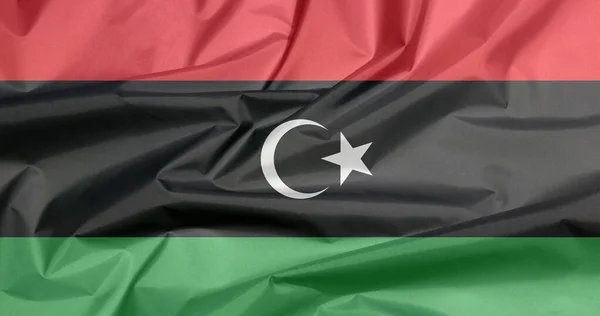 Fabric flag of Libya. Crease of Libyan flag background, red black and green with a white crescent and star.