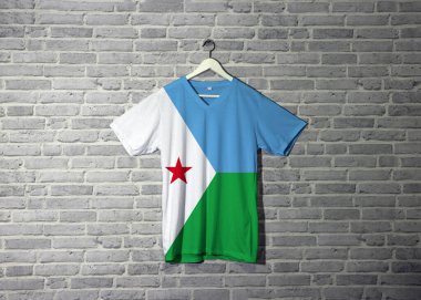 Gömlekte Cibuti bayrağı, duvarda da da tuğla desenli duvar kâğıdı asılı. Yatay açık mavi ve açık yeşil. Üzerinde kırmızı yıldız taşıyan beyaz bir üçgen var..