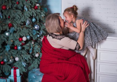 Kış tatili konsepti. İlham ve peri zamanı. Anne ve küçük kız Noel ağacının yakınındalar. Çok hoş sıcak tatil günleri, büyülü Noel zamanı.