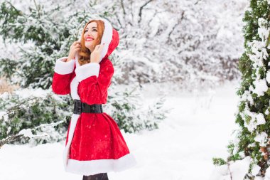 Mutlu Noeller ve mutlu Noeller! Karlı bir günde Noel Baba kız. Bebek dışarıda oyundan zevk alıyor. Park arka planında portre yapan kadın.