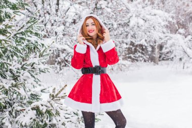 Mutlu Noeller ve mutlu Noeller! Karlı bir günde Noel Baba kız. Bebek dışarıda oyundan zevk alıyor. Park arka planında portre yapan kadın.