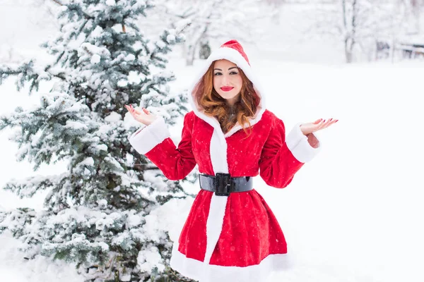 メリークリスマスと幸せな休日 雪の日のサンタの女の子 屋外でゲームを楽しんでる 冬の公園の背景の肖像画の女性 — ストック写真