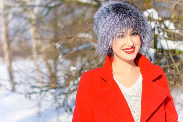漂亮的小女孩穿着红色外套 穿着冬装 白色毛衣 头戴狐狸皮帽 背景是大自然 时髦女士的阳光肖像 — 图库照片