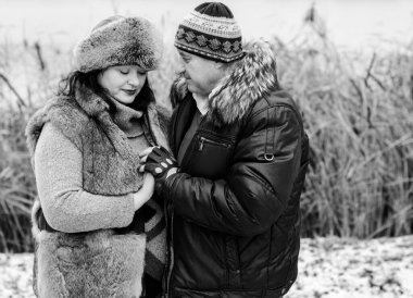 Kış parkının arka planında kışın veya sonbaharda tatilde ormanda eğlenen yaşlı bir çift. 40-50 yıl sonra aşk. Aşık Yetişkin Çift