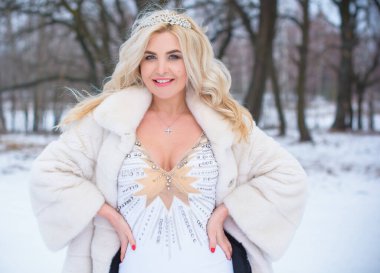 Tatil günleri, Noel kış zamanı. Zarif elbiseli ve kürklü bir kadın. Şık elbiseli bir kız, kadın modası konsepti, karlı havada sokakta poz veren.