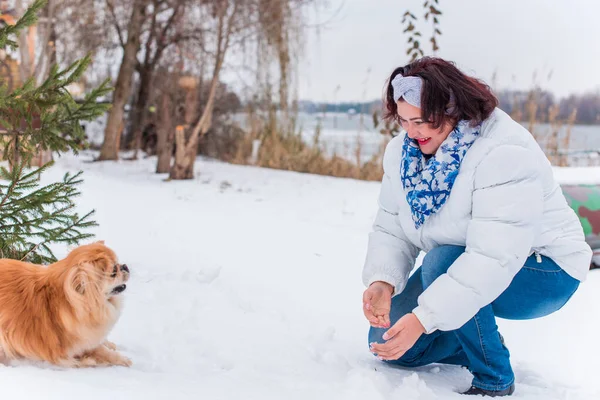Plus size elegant woman at winter day in park walking outdoor with her dog, Dog lover lady lifestyle, magic cold Christmas time with pet, Pets life