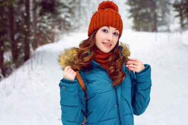 Kar içinde mutlu, sevimli bir kadın yukarı bakıyor. Kış havası temalı görüntüde gülümseyen genç bir kadın göl kıyısında, köyde kar tanelerini yakalamak için ellerini kaldırıyor.