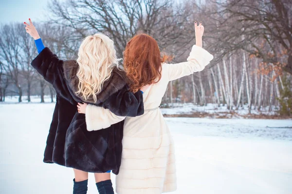 Best women friends ever. Two young nice girls spending time together at snowy winter park and cuddling on sunny day. Concept of women\'s friendship and relationship