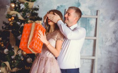 Noel hediyesi ile sürpriz yapan bir erkek ve kadının yeni yıl resmi. Noel 'i birlikte kutlayan çift. Güzel genç çift romantik bir yerde kutlama yapıyor..