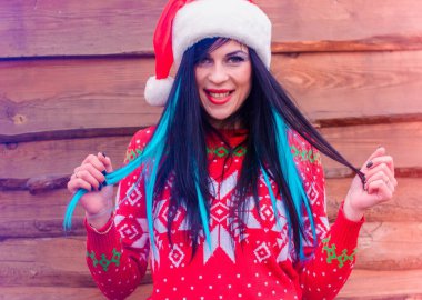 Ahşap arka planda genç bir bayanın olduğu Noel ve Yeni Yıl sahnesi. İyi tatiller. Örgü Noel süveteri ve şapkalı uzun saçlı güzel bir kız portresi.