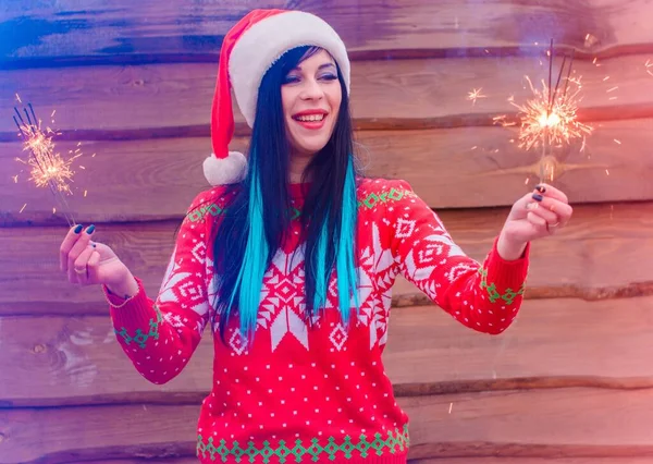 ニットのクリスマスセーターに青い髪の毛をした素敵な女の子と木製の背景の帽子はベンガルの光を保持し 新年とクリスマスに満足しています 冬の休日の奇跡と喜び — ストック写真