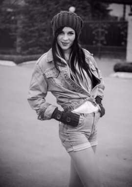 Kız kot ceket ve şort, beyaz bir kazak, örgü bir şapka ve eldiven giyiyor. Avrupa ve Amerikan kışları için günlük ve şık kıyafetler.