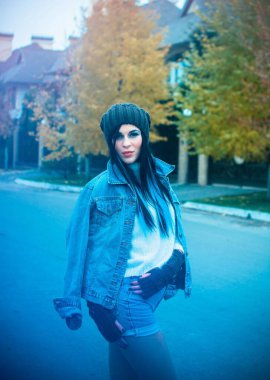 Kız kot ceket ve şort, beyaz bir kazak, örgü bir şapka ve eldiven giyiyor. Avrupa ve Amerikan kışları için günlük ve şık kıyafetler.