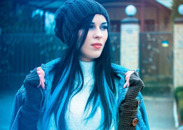 The girl is dressed in a denim jacket and shorts, a white sweater, a knitted hat and gloves. Winter Casual and stylish clothes for European and American winter.