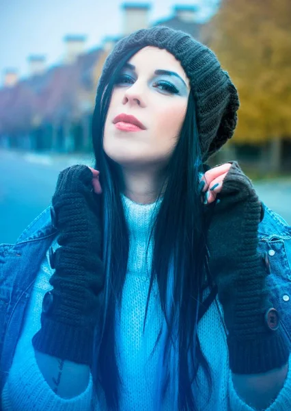 The girl is dressed in a denim jacket and shorts, a white sweater, a knitted hat and gloves. Winter Casual and stylish clothes for European and American winter.