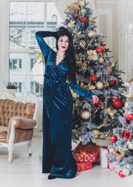 Evde Noel havası var. Güzel kilitleme. Zarif bir iç mekanda Noel ağacının yanında zarif bir kadın, kutsal Noel arifesi, hediyeler ve iyi ruh haliyle sihirli bir yeni yıl.