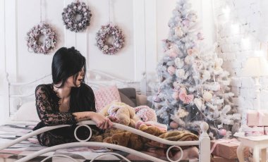 Evde Noel havası var. Güzel kilitleme. Zarif bir iç mekanda Noel ağacının yanında zarif bir kadın, kutsal Noel arifesi, hediyeler ve iyi ruh haliyle sihirli bir yeni yıl.