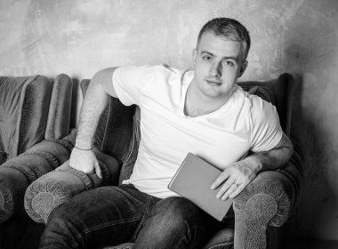 Gülümseyen mutlu bir adamın portresi. Beyaz Provence tarzıyla evde bir ekose üzerinde dinleniyor. Günlük yaşamda rahatlık, kış zamanı