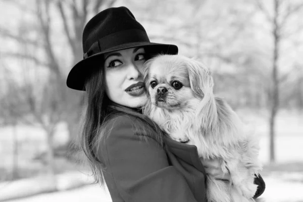 Woman pet owner walking at winter with her dog. Young lady with Pekingese dog walking. Tender feeling with a dog