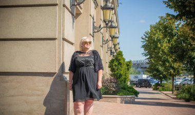 Şehirde yürüyüş yapan güzel bir kadın. Bahar - yaz zamanı. Sokaktaki orta yaşlı, güzel bir kadın. Vatandaş yaşam tarzı