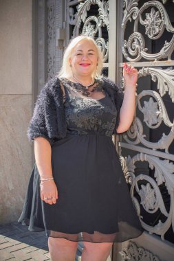 Şehirde yürüyüş yapan güzel bir kadın. Bahar - yaz zamanı. Sokaktaki orta yaşlı, güzel bir kadın. Vatandaş yaşam tarzı