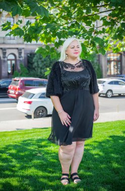 Şehirde yürüyüş yapan güzel bir kadın. Bahar - yaz zamanı. Sokaktaki orta yaşlı, güzel bir kadın. Vatandaş yaşam tarzı