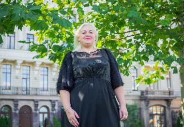 Şehirde yürüyüş yapan güzel bir kadın. Bahar - yaz zamanı. Sokaktaki orta yaşlı, güzel bir kadın. Vatandaş yaşam tarzı