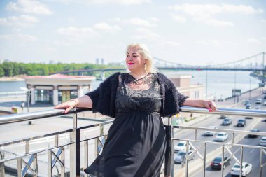 Şehirde yürüyüş yapan güzel bir kadın. Bahar - yaz zamanı. Sokaktaki orta yaşlı, güzel bir kadın. Vatandaş yaşam tarzı