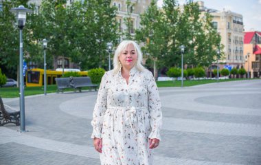 Şehirde yürüyüş yapan güzel bir kadın. Bahar - yaz zamanı. Sokaktaki orta yaşlı, güzel bir kadın. Vatandaş yaşam tarzı