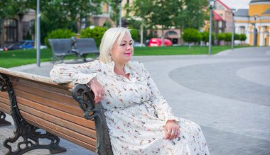 Şehirde yürüyüş yapan güzel bir kadın. Bahar - yaz zamanı. Sokaktaki orta yaşlı, güzel bir kadın. Vatandaş yaşam tarzı