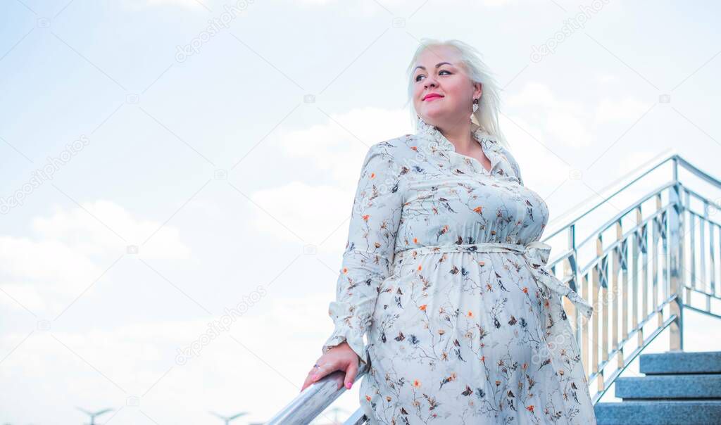 Beautiful woman on a walk in the city. Spring - summer time. A nice middle aged plus size woman at the street. Citizen lifestyle