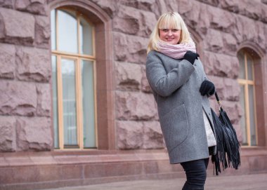 Şehirde yürüyüş yapan güzel, olgun bir kadın. Kış zamanı. Orta yaşlı, güzel bir kadın sokakta dikiliyor. Vatandaş yaşam tarzı