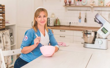 Güzel, modern bir kadın mutfaktaki masanın yanında duruyor. Mutfak konsepti, güzel mutfak iç mimarisi. 