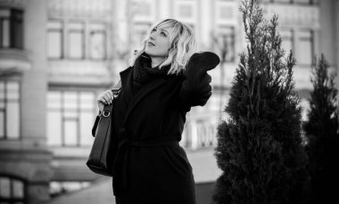 Hayat kavramı büyük şehirdeki modern kadın, yaşam tarzı vatandaşlar, ilkbahar ya da sonbahar günlerindeki kadın. Paltolu ve atkılı orta yaşlı bir kadın caddelerin ortasında yürüyor.