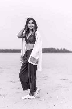 Seyahat konsepti. Sahilde genç bir kadının felsefi fotoğrafı. Kıyafetlerde minimalizm  