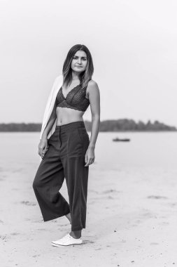 Seyahat konsepti. Sahilde genç bir kadının felsefi fotoğrafı. Kıyafetlerde minimalizm  